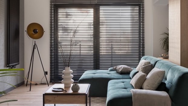 Dark blinds in a living room with a turquoise couch