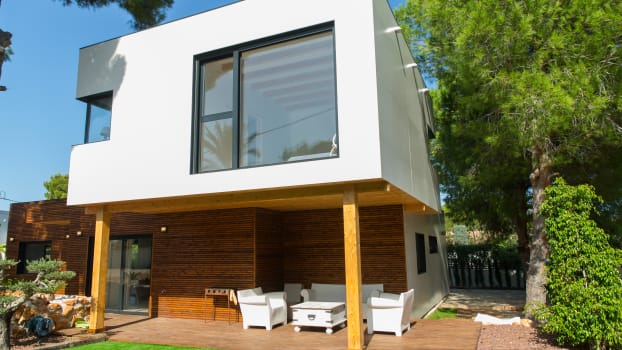 Construction de maison écologique en bois avec revêtement blanc et fenêtres extérieures en aluminium