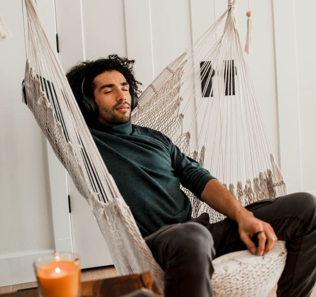 A man relaxing in a hanging rope chair in a living room