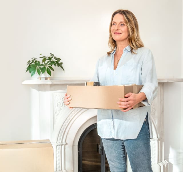 Woman carrying a moving box in a bright apartment