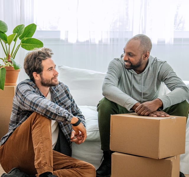 Two men sitting in front of moving boxes