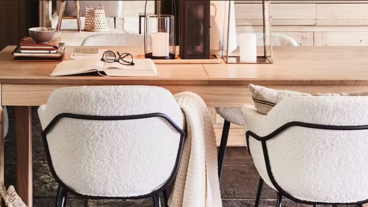 Salle à manger style scandinave avec table en bois et chaises en tissu bouclé blanc.