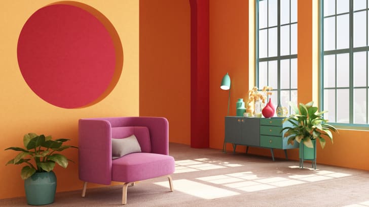 Intérieur style loft, murs orange, détails rouges, fauteuil rose, bahut turquoise.