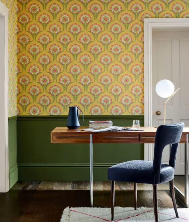 Bureau à la maison, table en bois, mur avec papier peint jaune à imprimé floral, partie peinturée en vert.