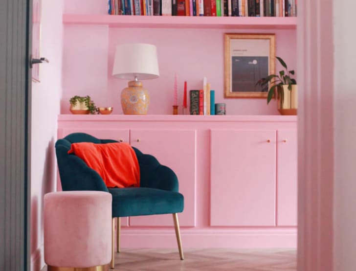 Salle de séjour, décor rose bonbon, bibliothèque, fauteuil et table d'appoint en velours