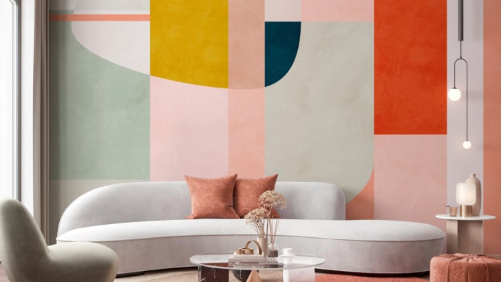 Salon, canapé design en courbes et mur peinturé avec formes géométriques.