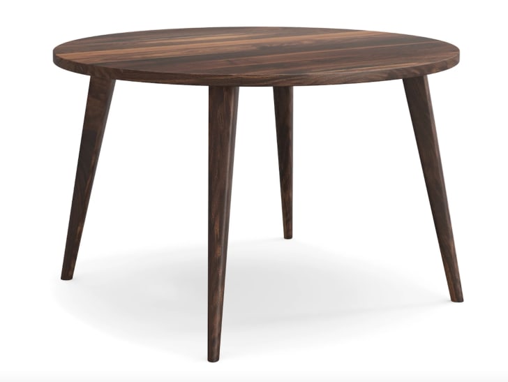 Table ronde en bois brun foncé, à pattes effilées