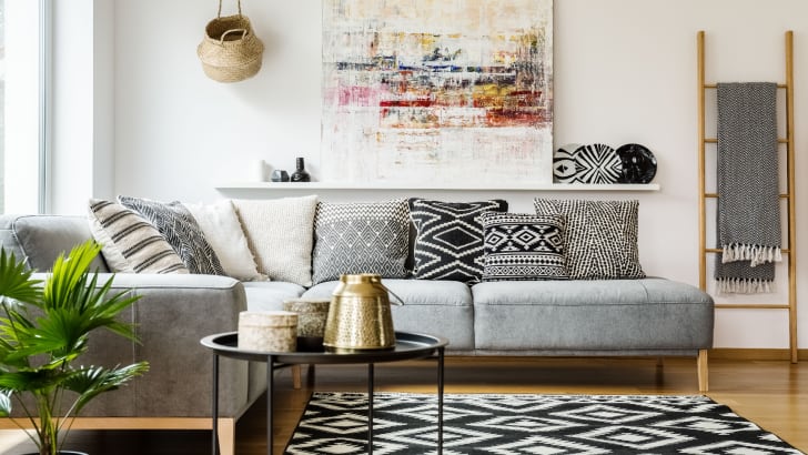 Salon avec tapis à motifs et coussins sur un canapé gris
