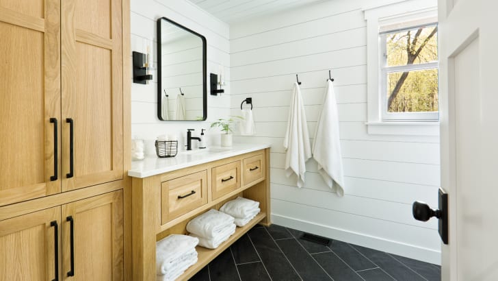 Salle de bains blanche contemporaine avec armoires en bois et quincaillerie noire