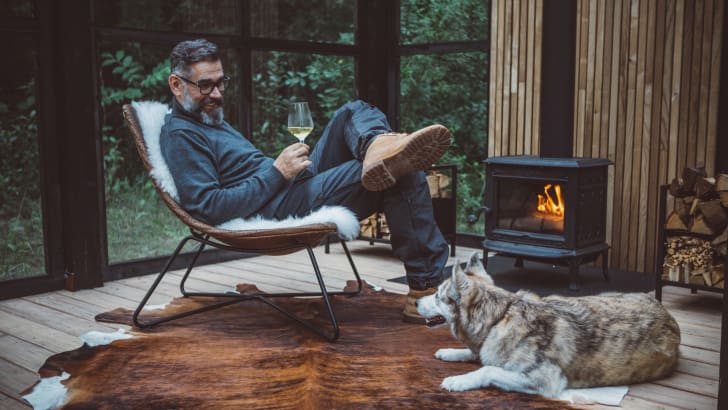Homme buvant du vin à côté du feu avec son chien