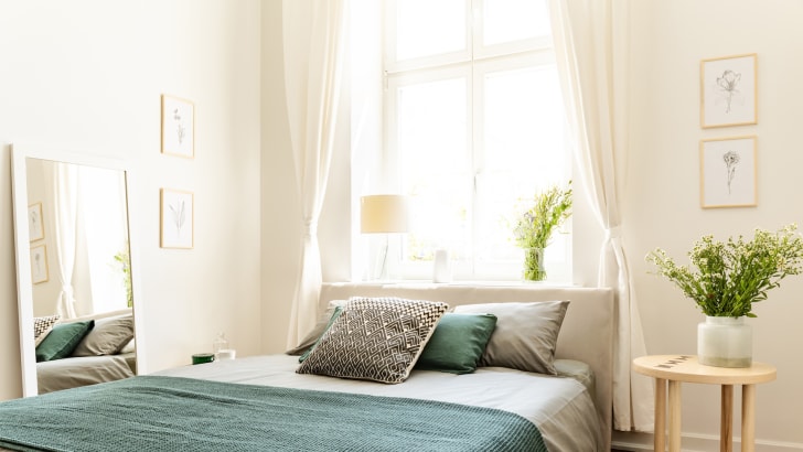 Draps et couverture en coton écologique sur un lit dans une chambre beignée de lumière