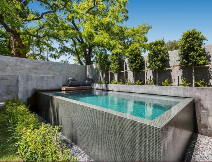 Belle piscine semi creusée, mur extérieur couvert mosaïque carrelage nuances de gris