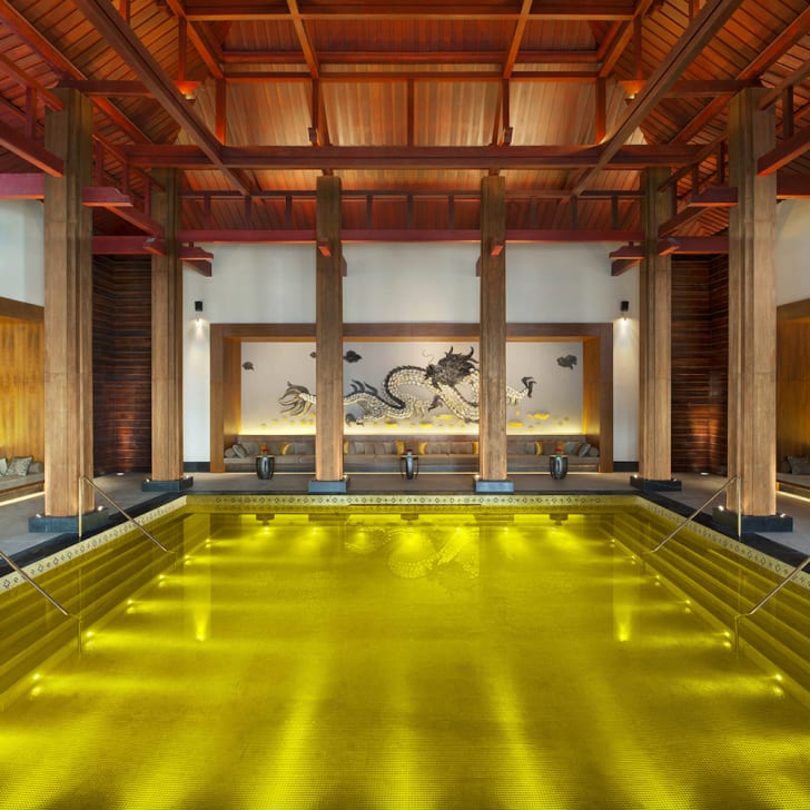 Belles piscines intérieur fond mosaïque dorée, mur avec motif de dragon, colonnes et plafond de bois