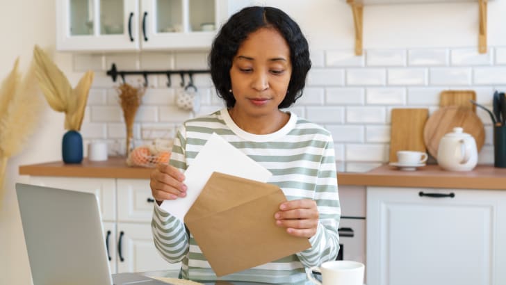 African-american woman preparing mail delivery in kitchen