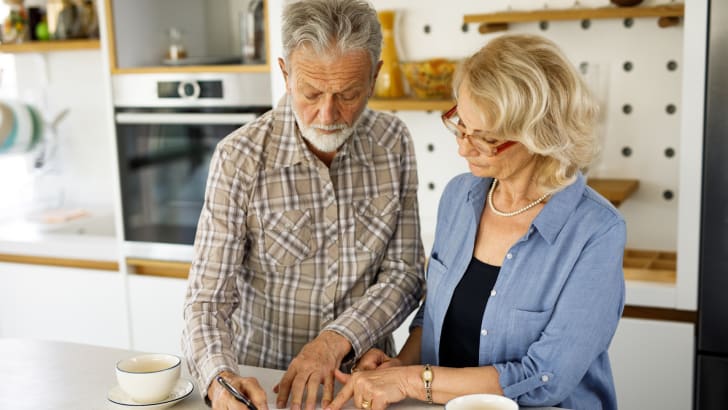 Couple de personnes âgées vérifiant leurs factures autour d'un café dans la cuisine
