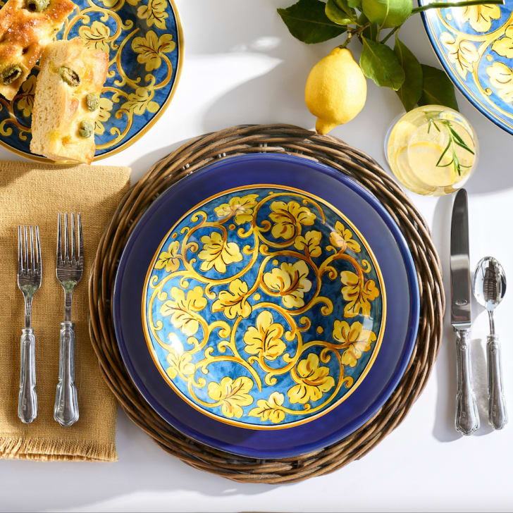 Déco voyage table avec assiettes en céramique bleue à feuilles jaunes, verre de limonade et pain aux olives