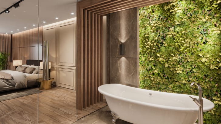 Salle de bain d’un appartement luxueux, avec une baignoire, un mur végétalisé et des luminaires