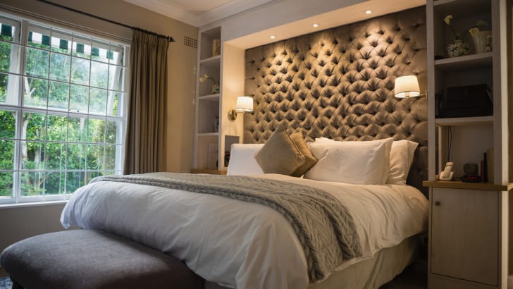 Chambre à coucher avec plafonniers intensifs encastrés et appliques murales illuminant la tête de lit