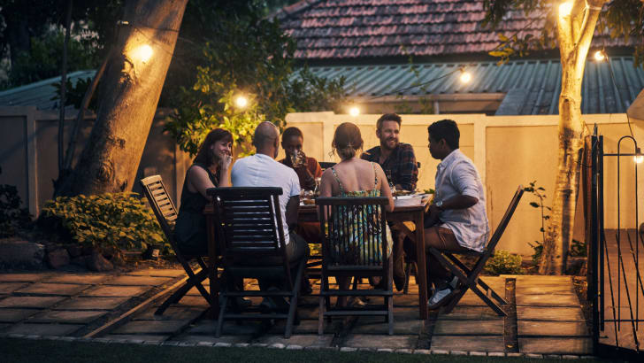 Group of friends having a dinner party outdoors on the patio