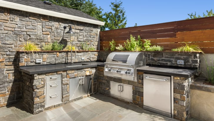 Terrasse de cour arrière aménagée avec une cuisine extérieure et un barbecue