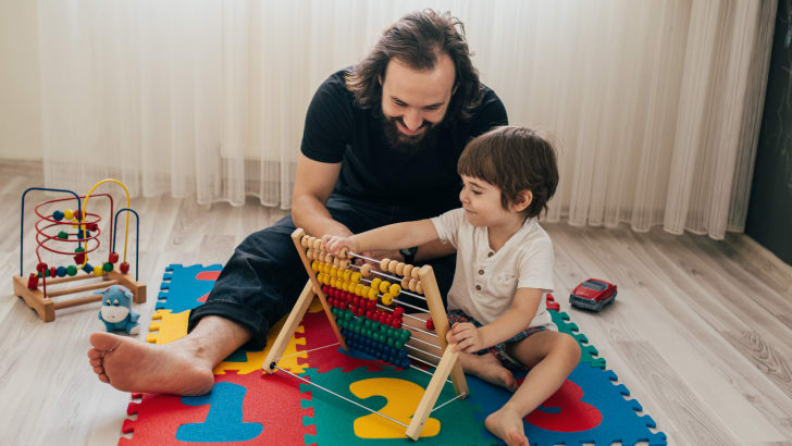 Father playing with son and abacus on foam mat floor tiles