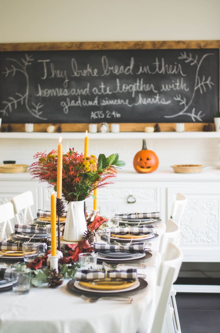 Idées de décorations d’Halloween à poser sur une table incluant une citrouille, des chandelles chaudes, des assiettes et des fleurs aux couleurs de l’automne