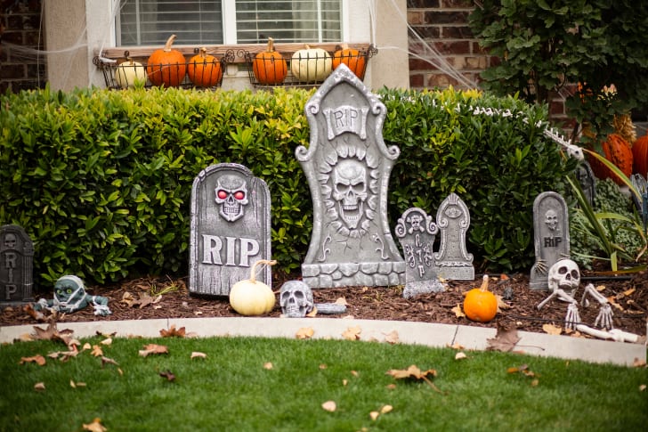 Vue extérieure d’une cour ornée de décorations d’Halloween, incluant des squelettes sortant de la terre, des pierres tombales et des citrouilles