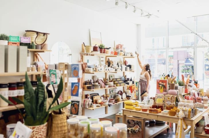 Vue d'ensemble sur la boutique de décoration Bouchée bée incluant des plantes, des bols, des assiettes, de la papeterie et une personne cliente