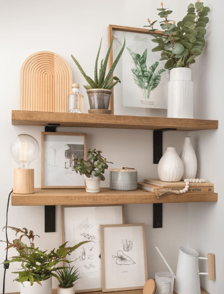 Tablettes de bois sur lesquelles sont posés des accessoires décoratifs comme des vases, des plantes, des cadres, une lampe