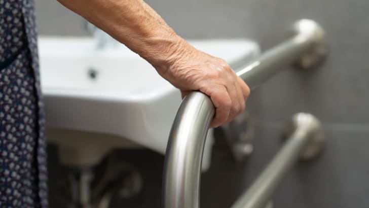 Femme âgée tenant une barre d’appui près d’un lavabo