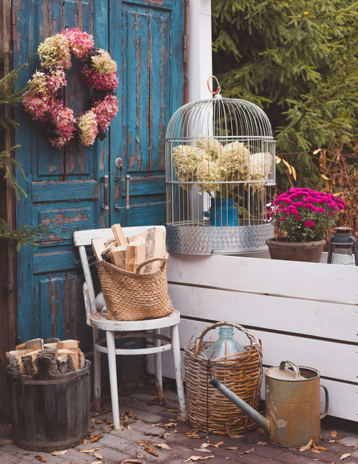 Ensemble de décorations rustiques dans un jardin d'automne près de la maison, couronne d'hortensias, vieux instruments, fleurs colorées en pot, vieilles portes bleues