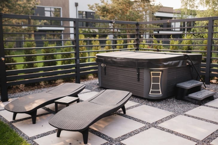  A whirlpool bath and sun loungers in the corner of the terrace of an outdoor courtyard surrounded by fencing