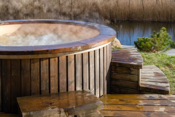 Outdoor wooden Jacuzzi in front of a river, where steam from the hot water evaporates