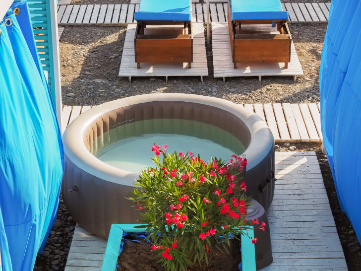 Inflatable spa on a wooden walkway in a spa area, surrounded by sun loungers and flowers