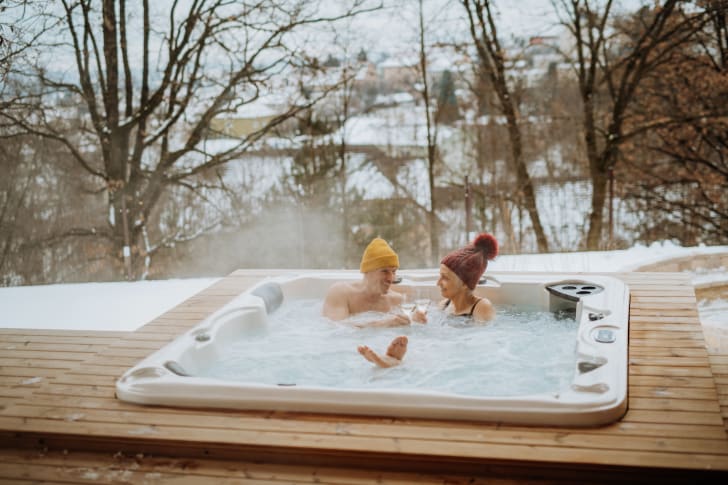 Couple sénior profitant d'un bain à remous et d’instants de relaxation sur une terrasse en plein air avec un verre de vin