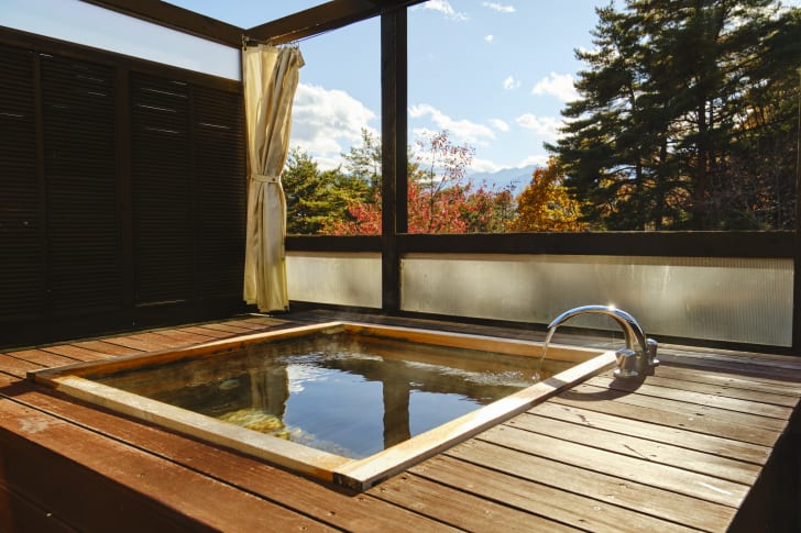 Outdoor spa set into a wooden platform in front of colorful autumn trees