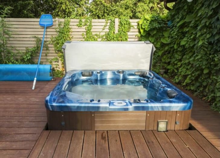 Wooden spa area with spa kit on a terrace surrounded by greenery