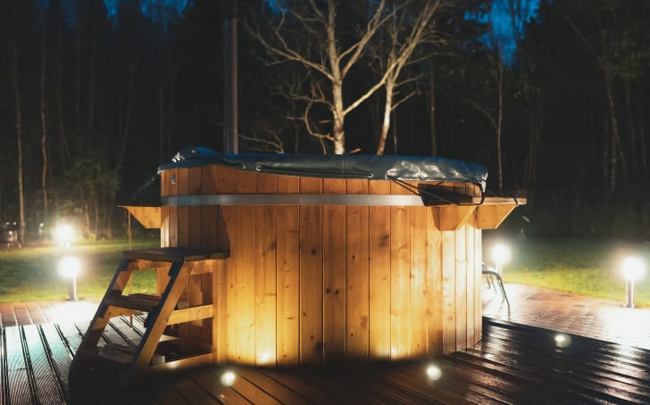 Wooden whirlpool surrounded by lights set into the floor of a terrace