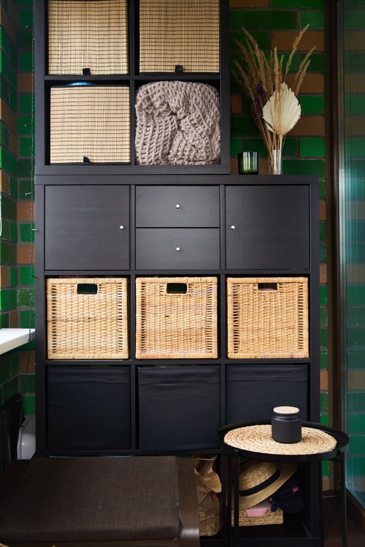 Wicker storage boxes and baskets on a black shelf in a small bathroom