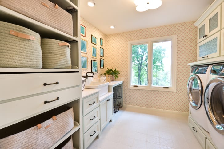 Interior design of a home's laundry room and powder room, including front-loading washer and dryer, storage space and sink