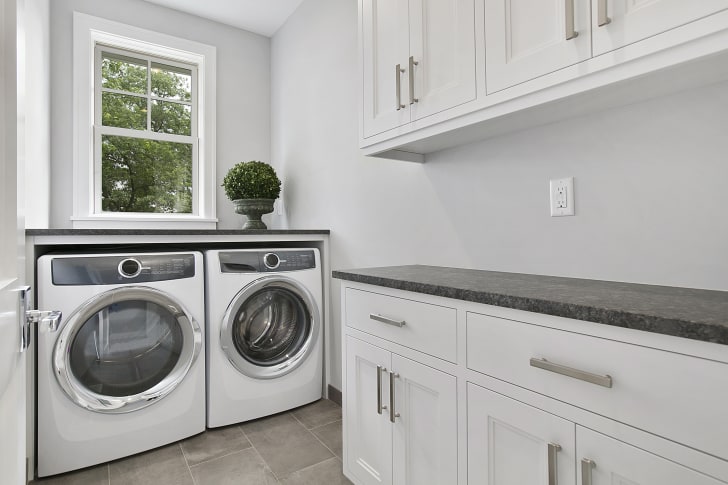 White laundry room with worktop for folding laundry, front-loading cabinets and appliances    