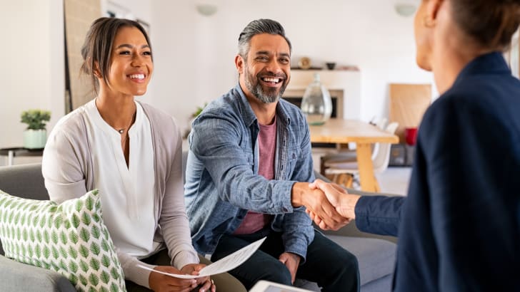 Couple smiling and shaking hands with a realtor