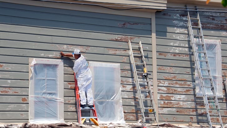 Travailleur qui enlève de la peinture au plomb sur un bâtiment