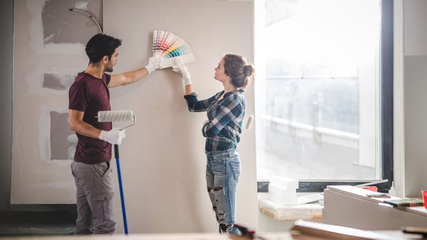 Young couple choosing a colour for the wall in their home