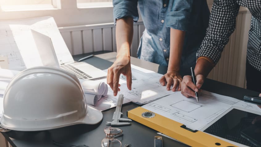Close-up of two people looking over blueprints and building plans