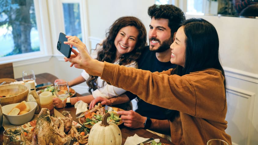 Three friends taking a selfie at their Friendsgiving table