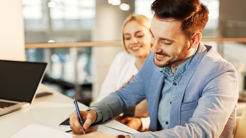 Couple smiling and signing papers