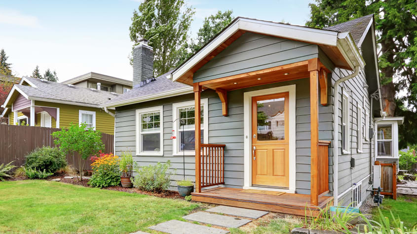 Petite maison avec revêtement gris et galerie en bois
