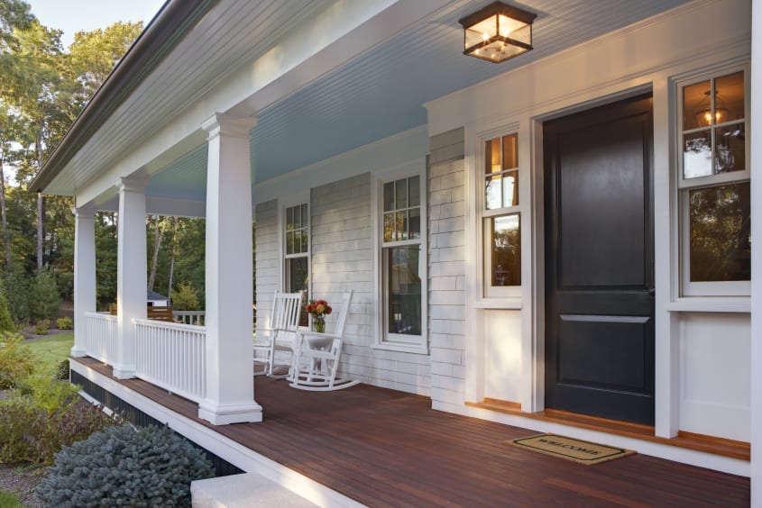Photo of a home façade with a colourful front door, modern exterior lighting, and well-maintained flower beds