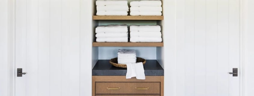 White towels stored in an alcove on made-to-measure shelving and a drawer